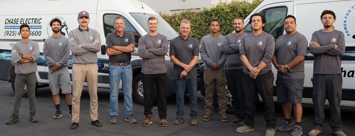 The Chase Electric team standing together in front of company vans